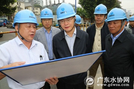 韶关水司经理甘志高（左一）向蓝佛安书记（中）介绍工程建设情况